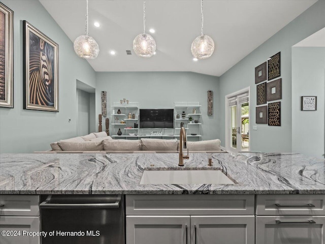 kitchen with pendant lighting, stainless steel dishwasher, light stone countertops, and sink