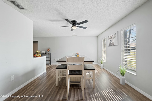 dining space with ceiling fan, dark hardwood / wood-style flooring, and a textured ceiling