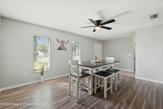 dining area featuring a textured ceiling, ceiling fan, and dark wood-type flooring