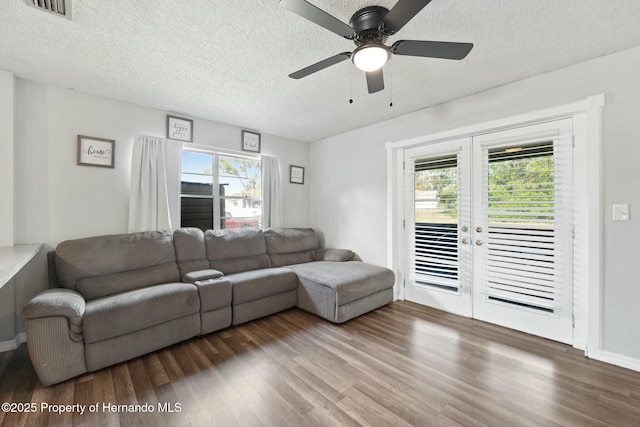 living room with a wealth of natural light, dark hardwood / wood-style flooring, and ceiling fan