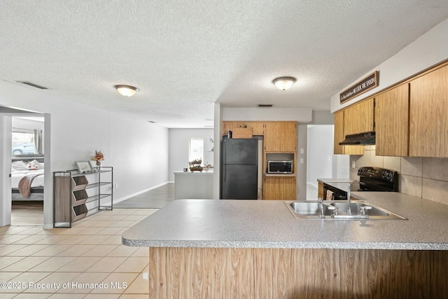 kitchen with kitchen peninsula, backsplash, exhaust hood, sink, and black appliances