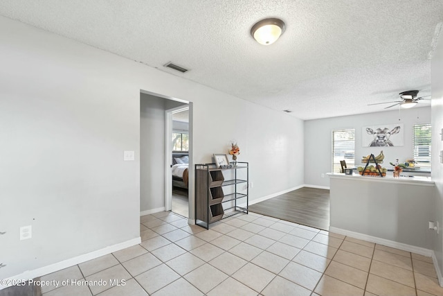 tiled spare room featuring a textured ceiling and ceiling fan