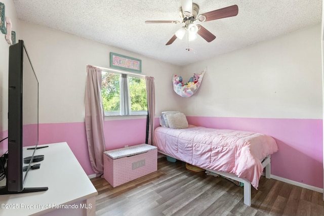 bedroom with ceiling fan, wood-type flooring, and a textured ceiling