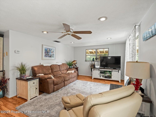 living room featuring a textured ceiling, light hardwood / wood-style floors, and ceiling fan