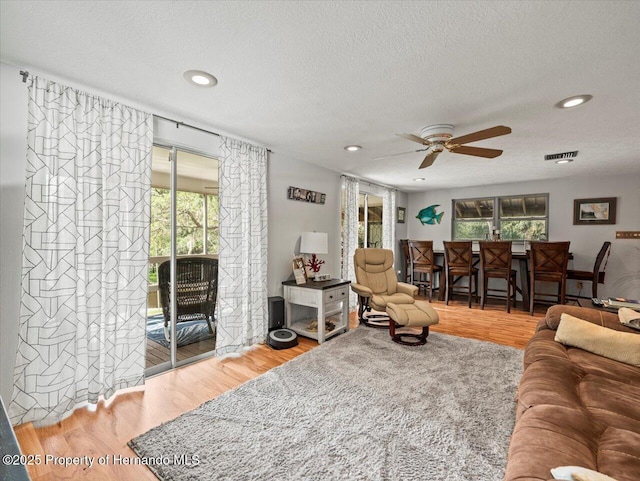 living room with ceiling fan, wood-type flooring, and a textured ceiling