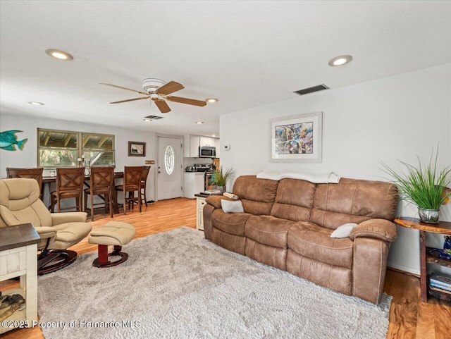 living room with ceiling fan and light hardwood / wood-style floors