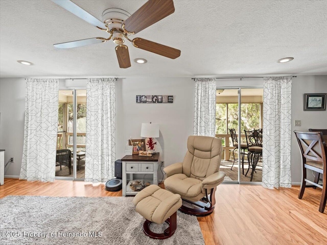 living area featuring a textured ceiling, hardwood / wood-style flooring, and ceiling fan