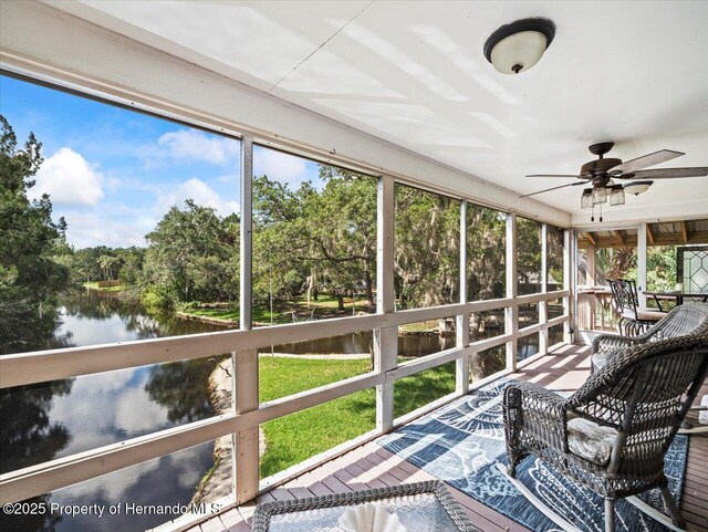 sunroom featuring ceiling fan and a water view