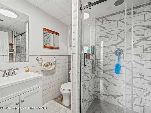 bathroom featuring a drop ceiling, vanity, an enclosed shower, and toilet