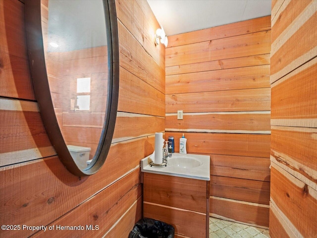 bathroom featuring vanity, toilet, and wooden walls