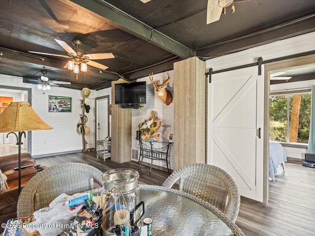 interior space featuring ceiling fan, a barn door, and dark hardwood / wood-style flooring