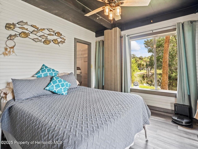 bedroom featuring hardwood / wood-style floors, ceiling fan, a walk in closet, and multiple windows