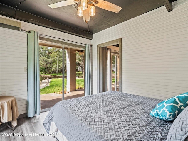 bedroom featuring access to exterior, ceiling fan, wood walls, and light wood-type flooring