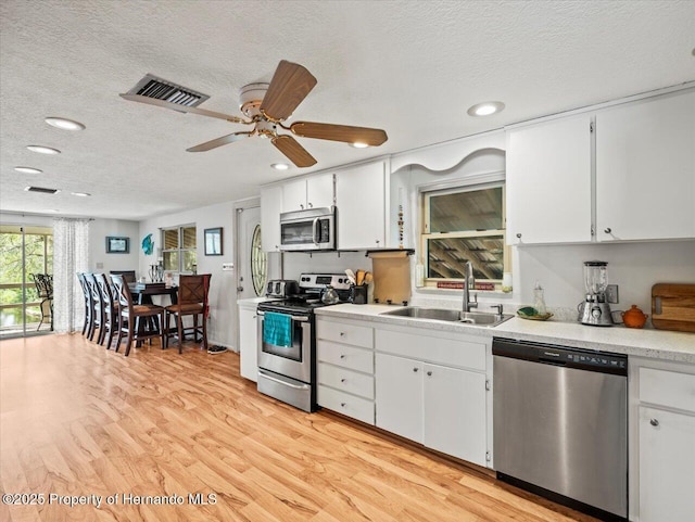 kitchen featuring a textured ceiling, light hardwood / wood-style floors, sink, and appliances with stainless steel finishes