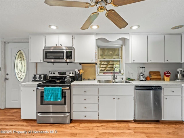 kitchen featuring sink, white cabinets, stainless steel appliances, and a textured ceiling