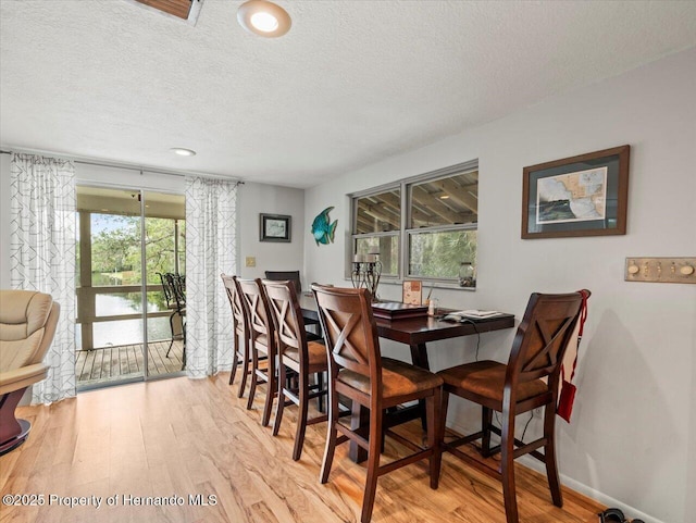 dining space with light wood-type flooring and a textured ceiling