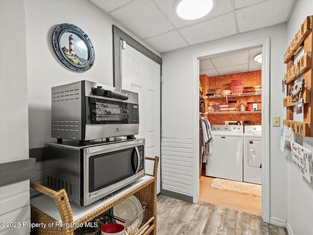 kitchen with a paneled ceiling, washing machine and dryer, and light wood-type flooring