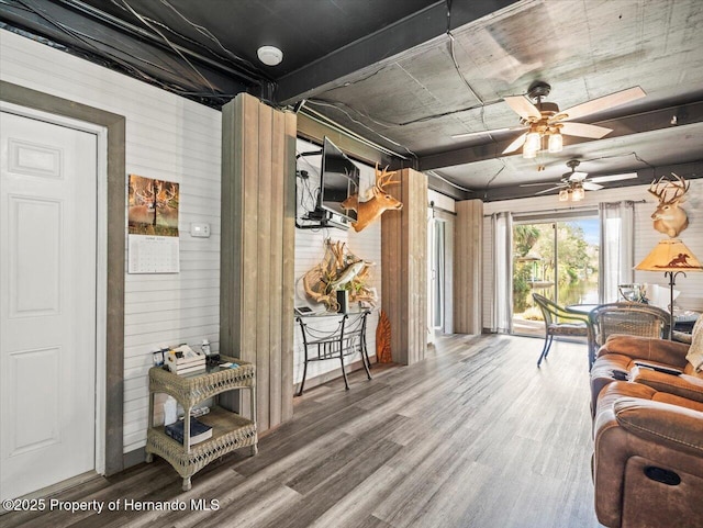 living room with hardwood / wood-style floors, ceiling fan, and wood walls