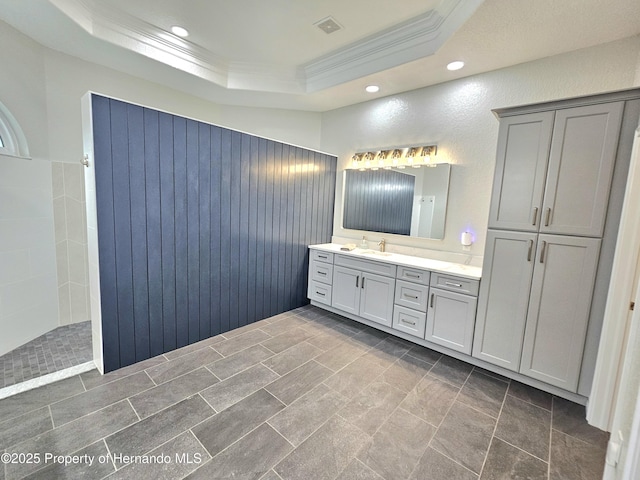 bathroom featuring a tray ceiling, crown molding, and vanity