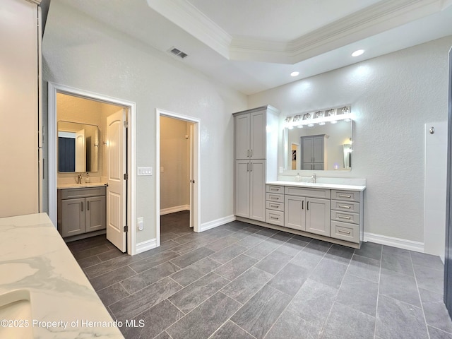 bathroom with a tray ceiling, crown molding, and vanity