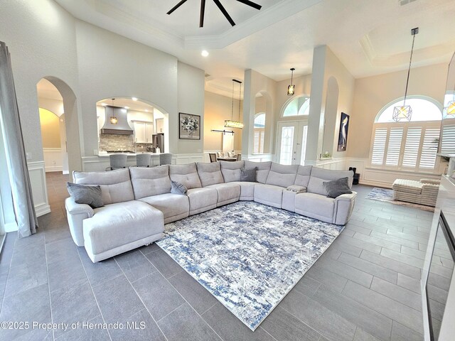 living room with a chandelier, a high ceiling, a raised ceiling, and ornamental molding