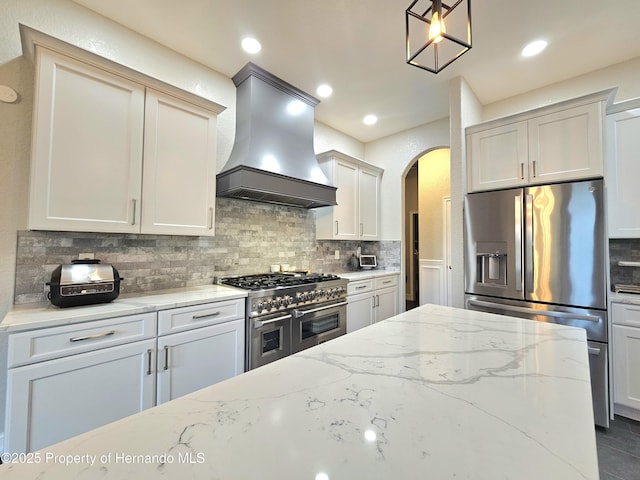 kitchen with pendant lighting, light stone countertops, tasteful backsplash, custom range hood, and stainless steel appliances