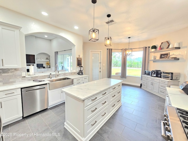 kitchen featuring pendant lighting, dishwasher, sink, light stone countertops, and white cabinetry