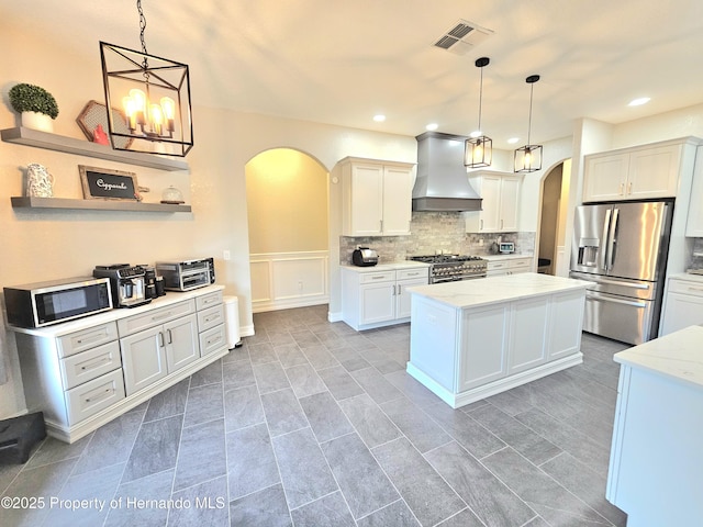 kitchen with pendant lighting, premium range hood, a kitchen island, white cabinetry, and stainless steel appliances