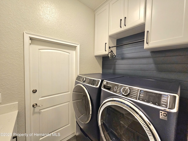 clothes washing area featuring washer and dryer and cabinets