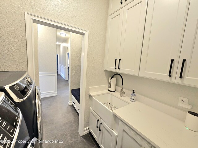 washroom featuring washing machine and clothes dryer, sink, and cabinets