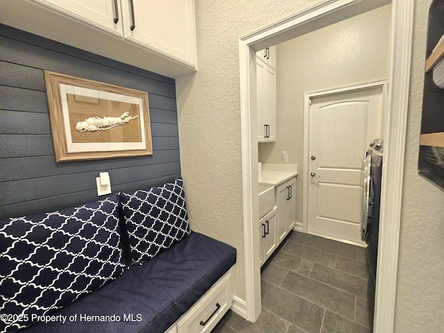 mudroom featuring dark tile patterned flooring and wood walls