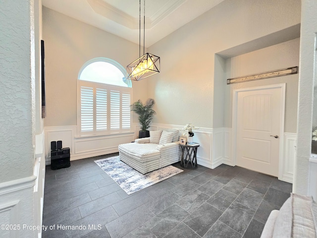 living area with a raised ceiling and ornamental molding