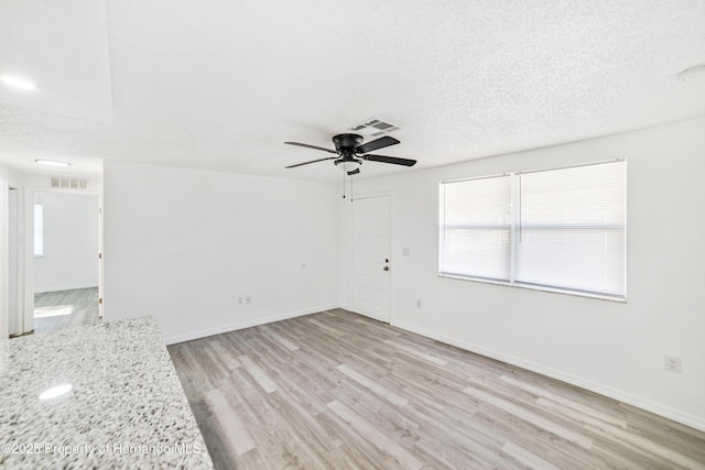 spare room featuring ceiling fan, a textured ceiling, and light hardwood / wood-style flooring