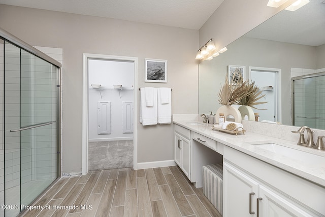 bathroom featuring a textured ceiling, vanity, and a shower with door