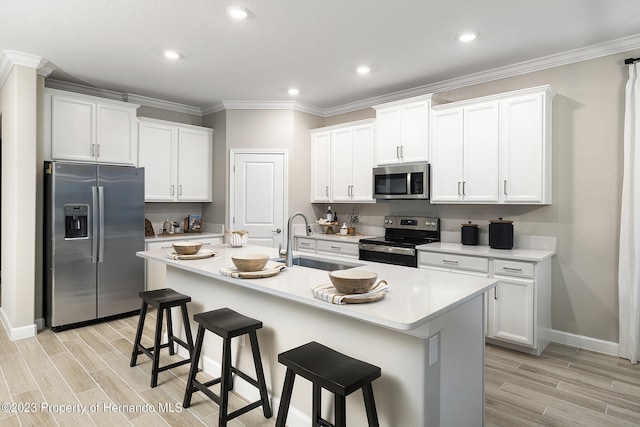 kitchen with sink, white cabinetry, stainless steel appliances, and a kitchen island with sink