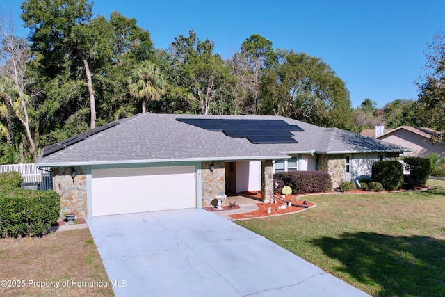 single story home with a front yard, a garage, and solar panels