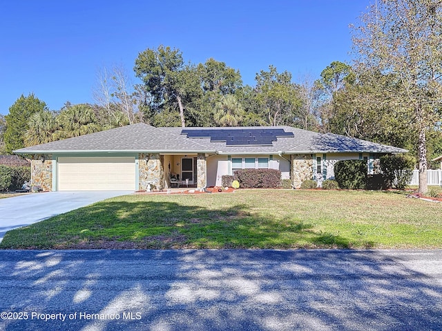 ranch-style home with solar panels, a front lawn, and a garage