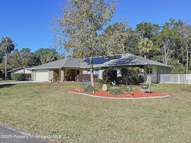 ranch-style house with solar panels, a front yard, and a garage