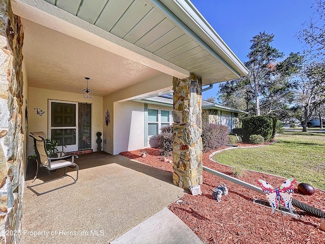 entrance to property featuring a yard and a patio