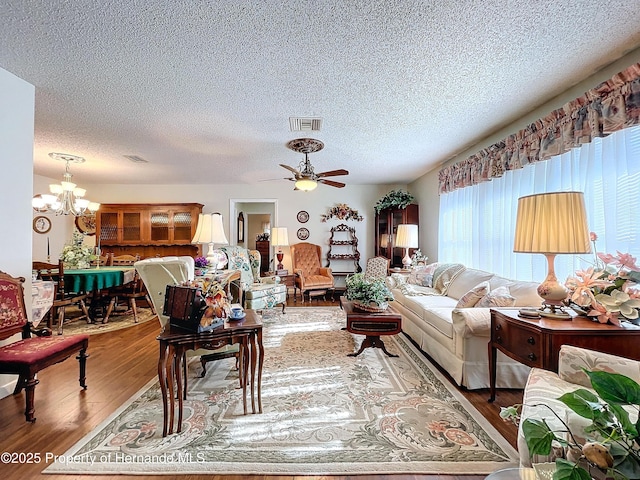 living room featuring ceiling fan with notable chandelier, a textured ceiling, and wood-type flooring