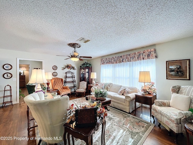 living room with dark wood-type flooring, a textured ceiling, and ceiling fan