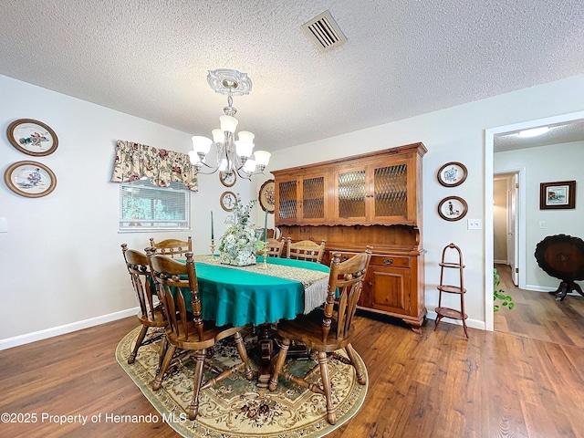 dining room featuring a textured ceiling, a chandelier, and dark hardwood / wood-style floors