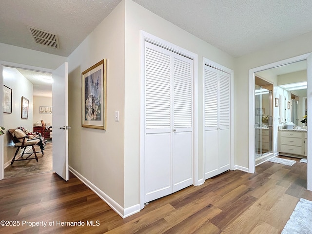 hallway with hardwood / wood-style flooring and a textured ceiling