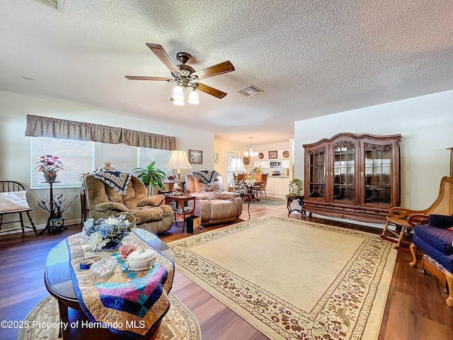 living room with ceiling fan with notable chandelier, a textured ceiling, and hardwood / wood-style floors