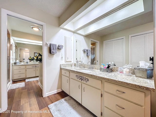 bathroom with wood-type flooring, vanity, and a textured ceiling