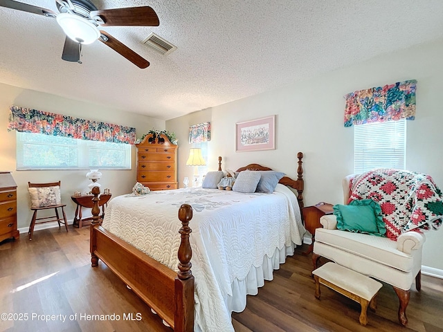 bedroom featuring dark hardwood / wood-style flooring, a textured ceiling, ceiling fan, and multiple windows