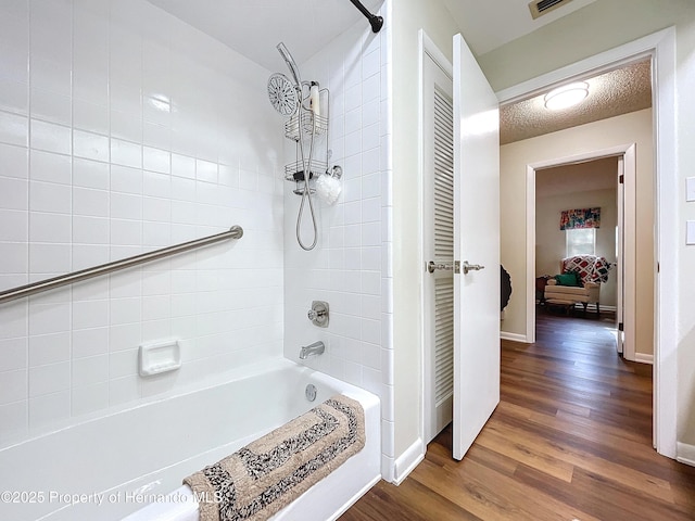 bathroom featuring a textured ceiling, tiled shower / bath combo, and hardwood / wood-style flooring