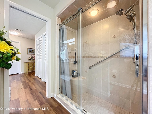 bathroom with wood-type flooring, walk in shower, and a textured ceiling