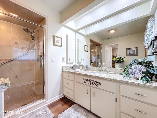 bathroom with wood-type flooring, walk in shower, and vanity