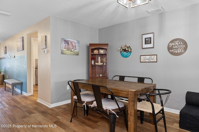 dining area featuring a textured ceiling and hardwood / wood-style flooring